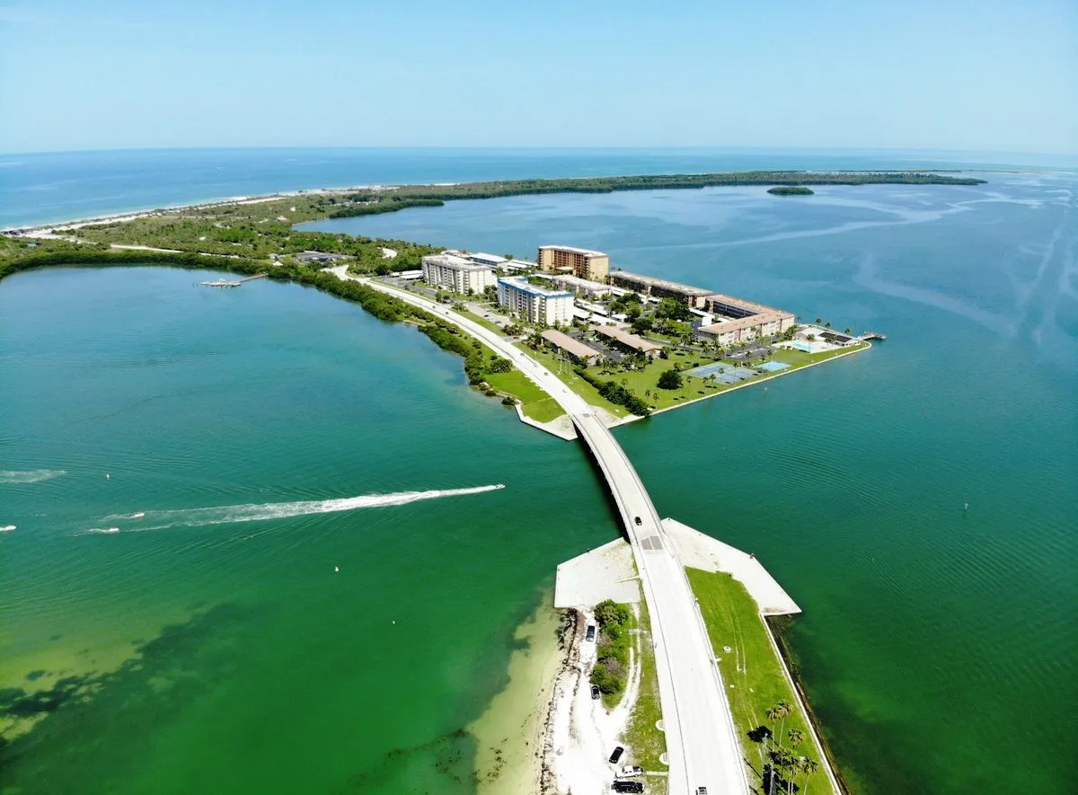 Aerial view of the Dunedin Causeway crossing green Gulf water toward Honeymoon Island.