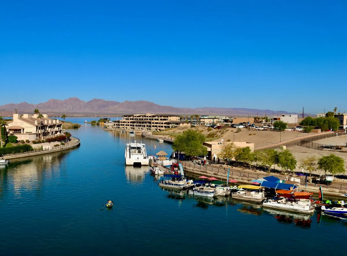 Boats moored along the Bridgewater Channel in Lake Havasu City, seen from London Bridge, with desert mountains on the horizon.