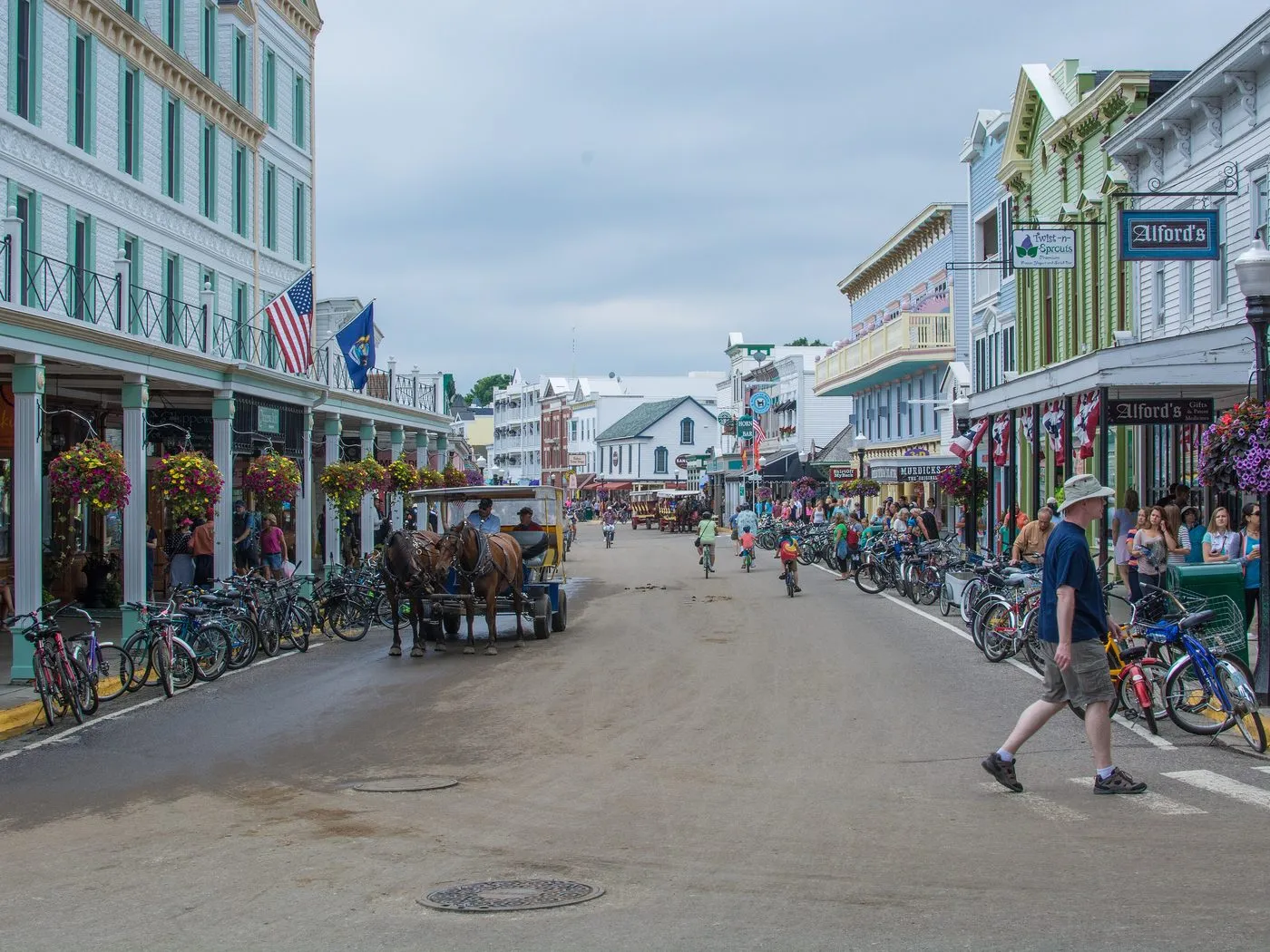 Main Street on Mackinac Island, lined with parked bicycles, with a horse-drawn carriage in the road and no cars.