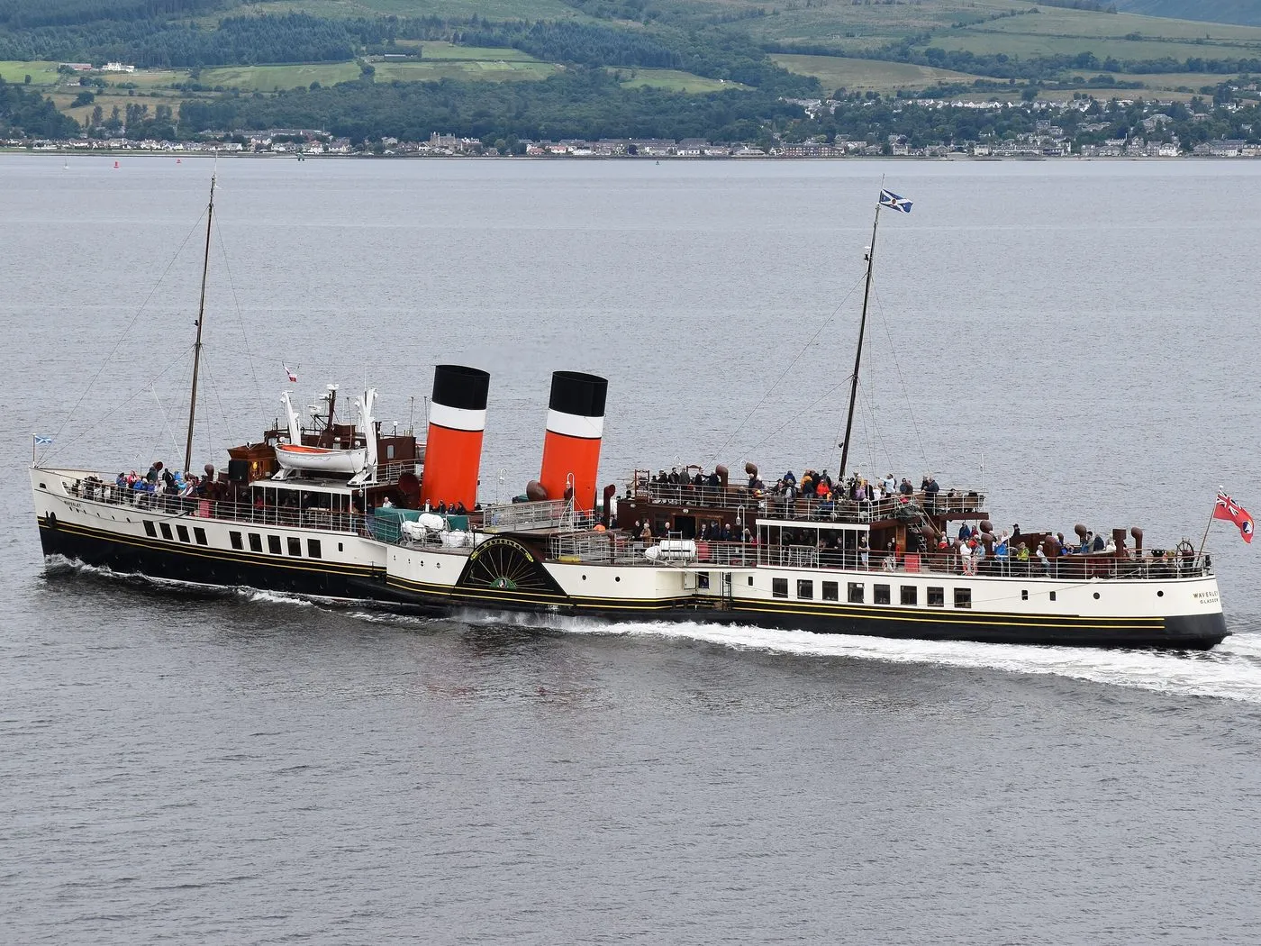The paddle steamer Waverley under way, with two red, white and black funnels and decks full of passengers.