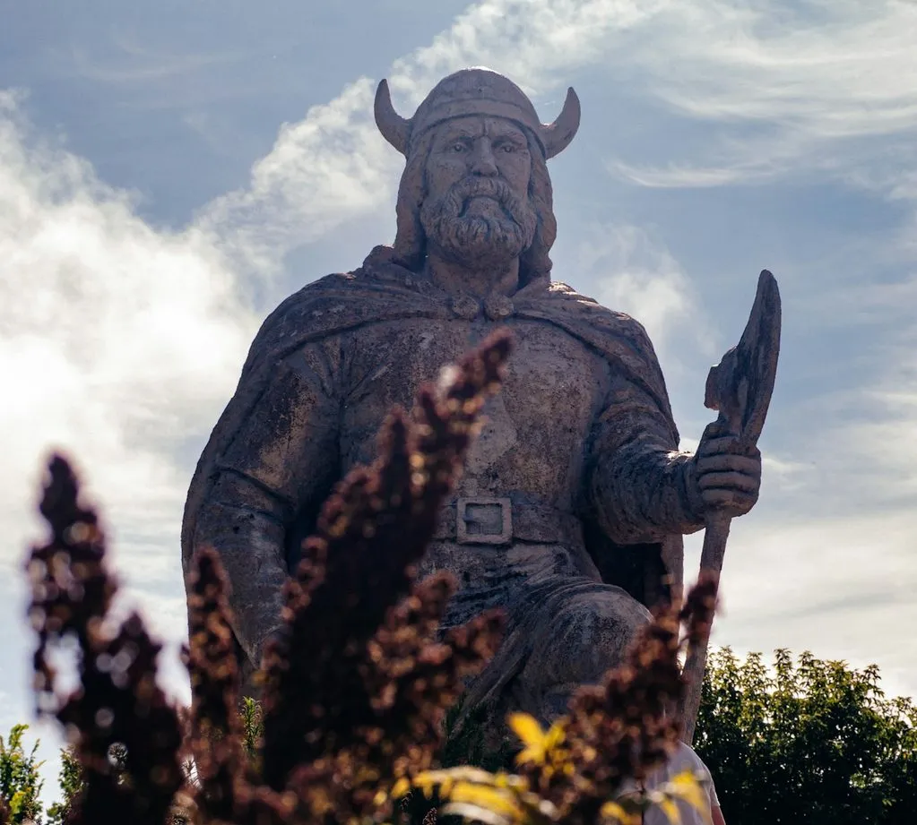 The Viking statue at Gimli, a bearded figure in a horned helmet holding an axe, against a bright sky.