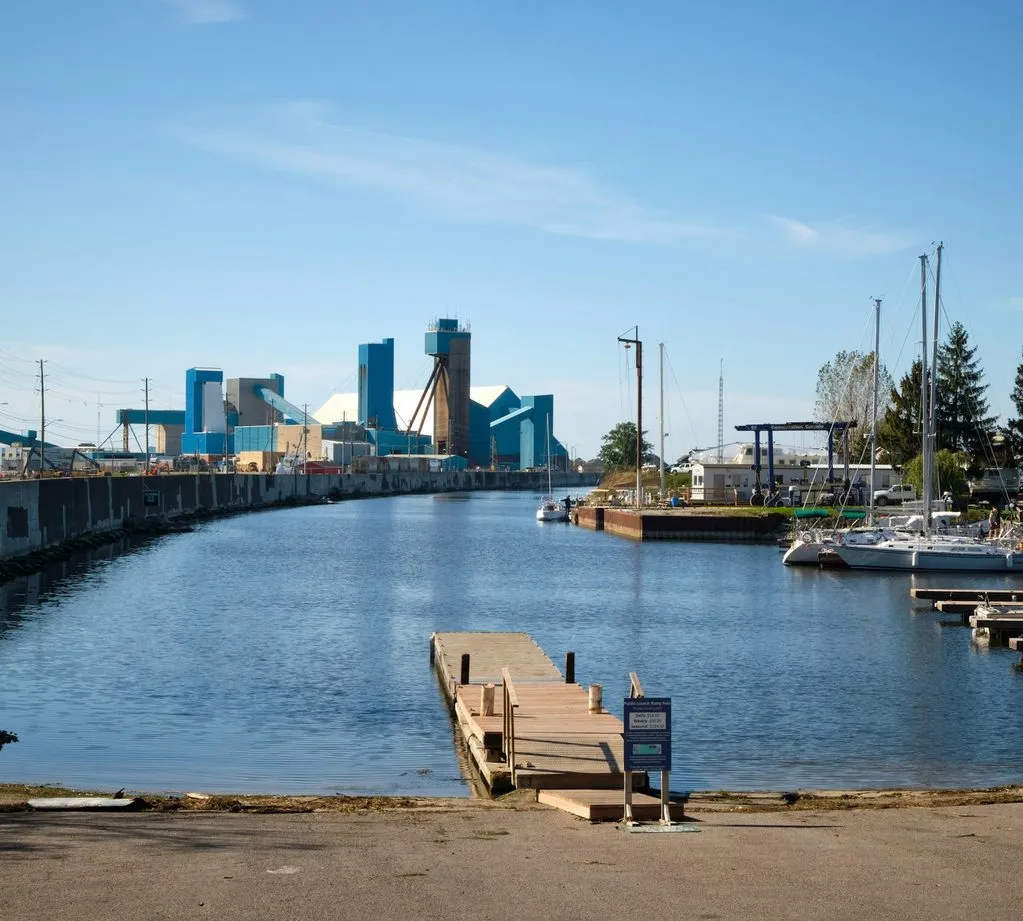 Goderich harbour on a clear day, with the blue buildings of the salt mine behind a small marina and a boat launch.
