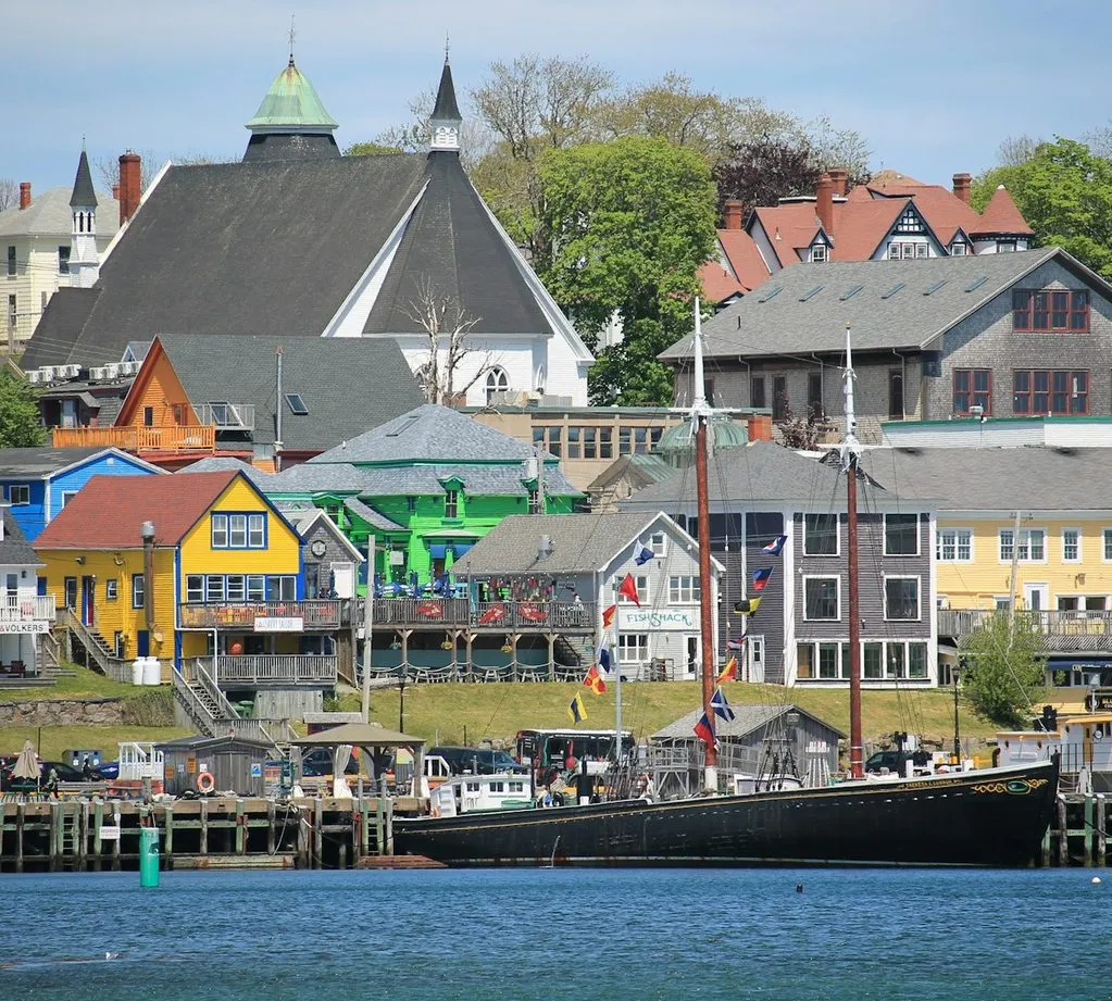 Brightly painted waterfront buildings and a moored sailing ship in Lunenburg, Nova Scotia.