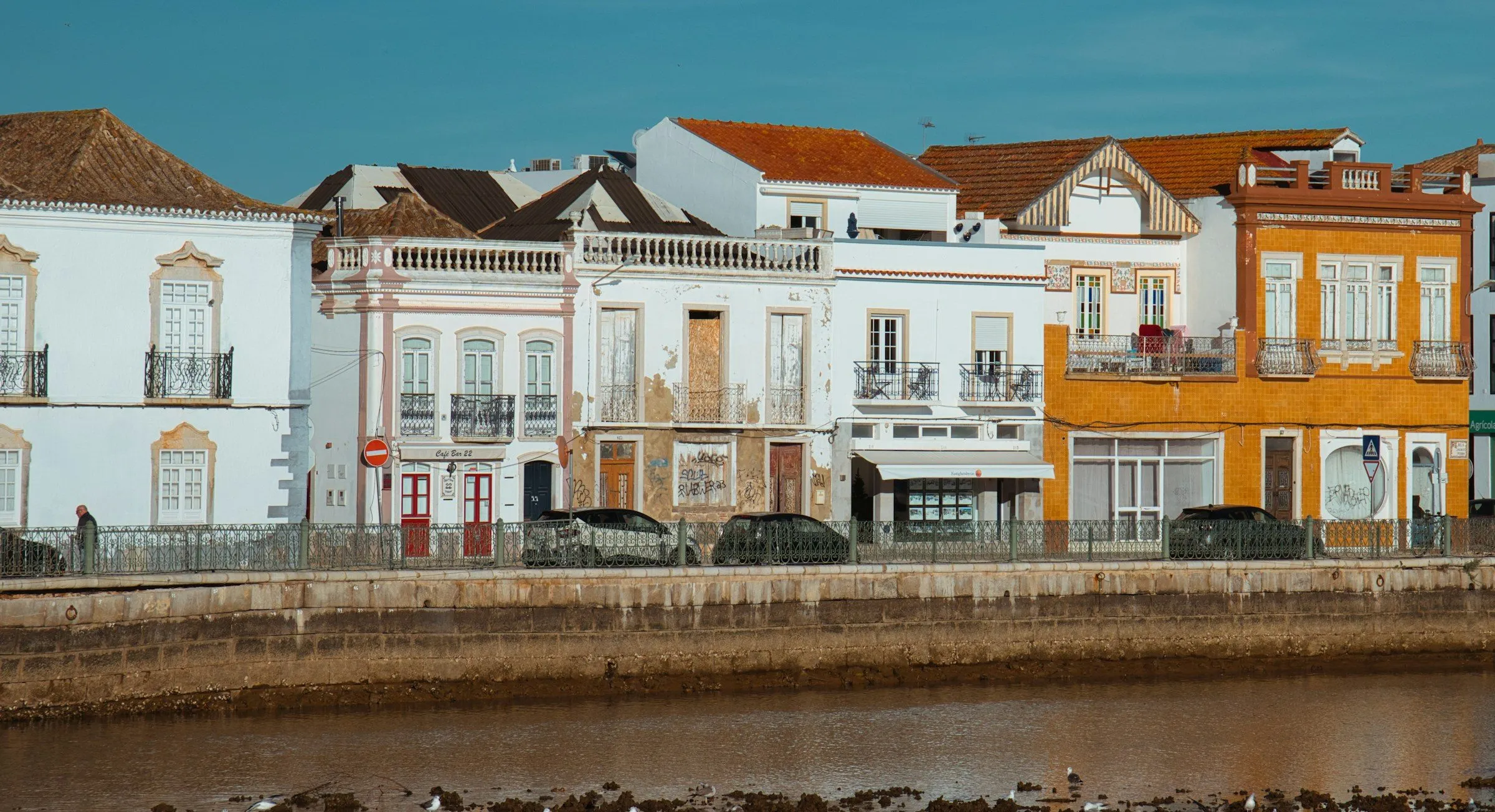 White, tiled and ochre townhouses along the river in Tavira at low tide.