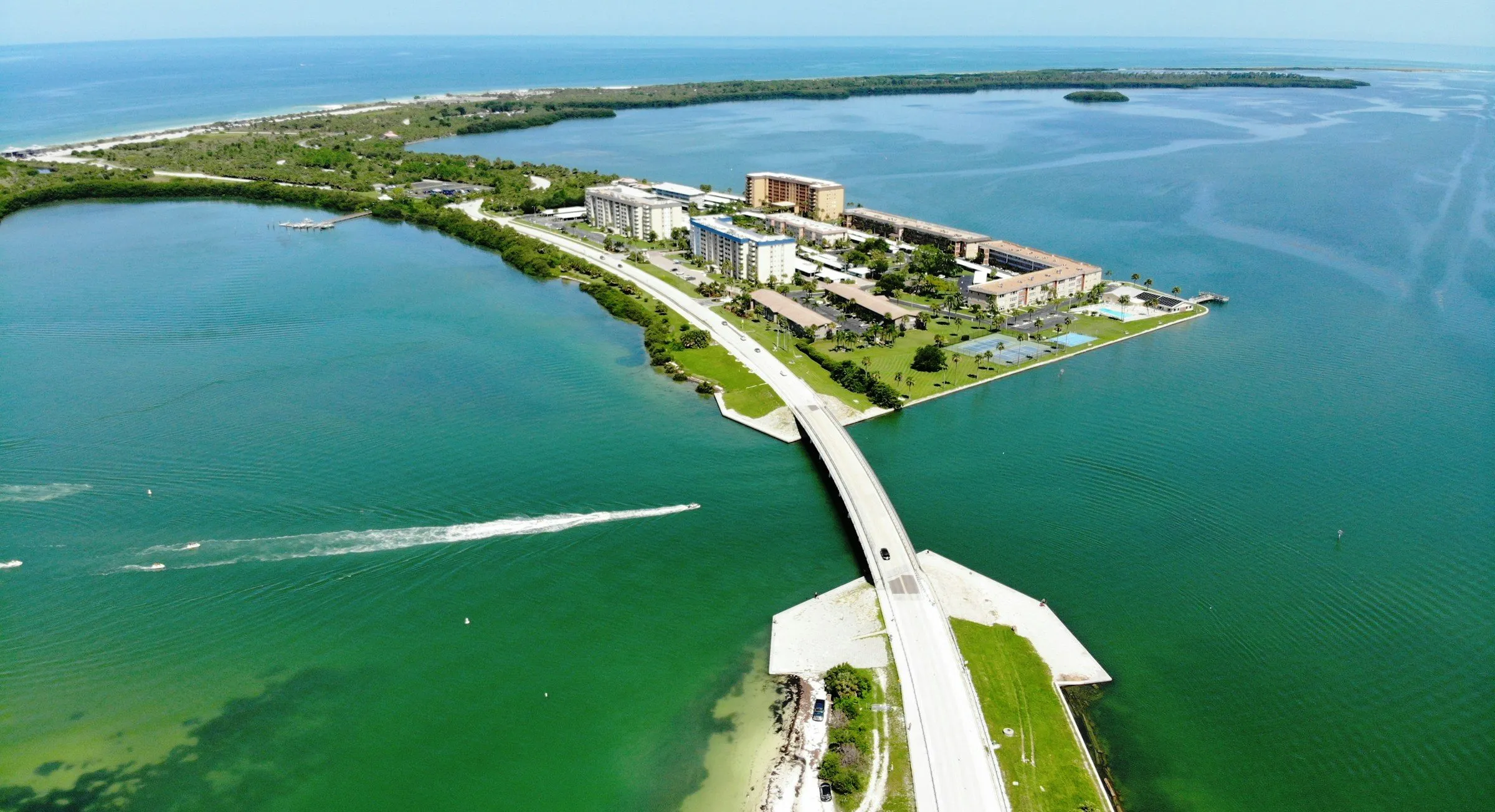 Aerial view of the Dunedin Causeway crossing green Gulf water toward Honeymoon Island.
