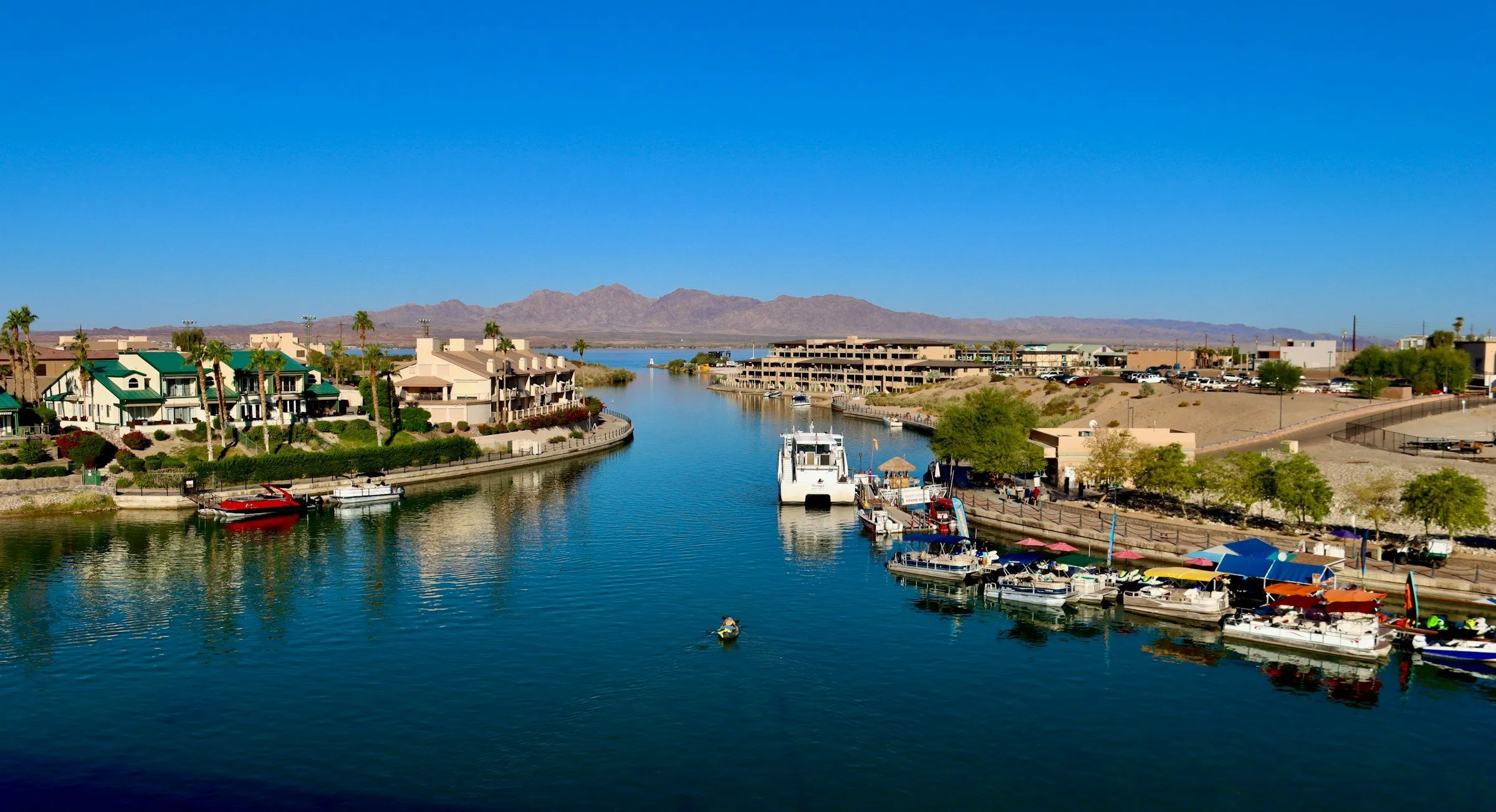 Boats moored along the Bridgewater Channel in Lake Havasu City, seen from London Bridge, with desert mountains on the horizon.