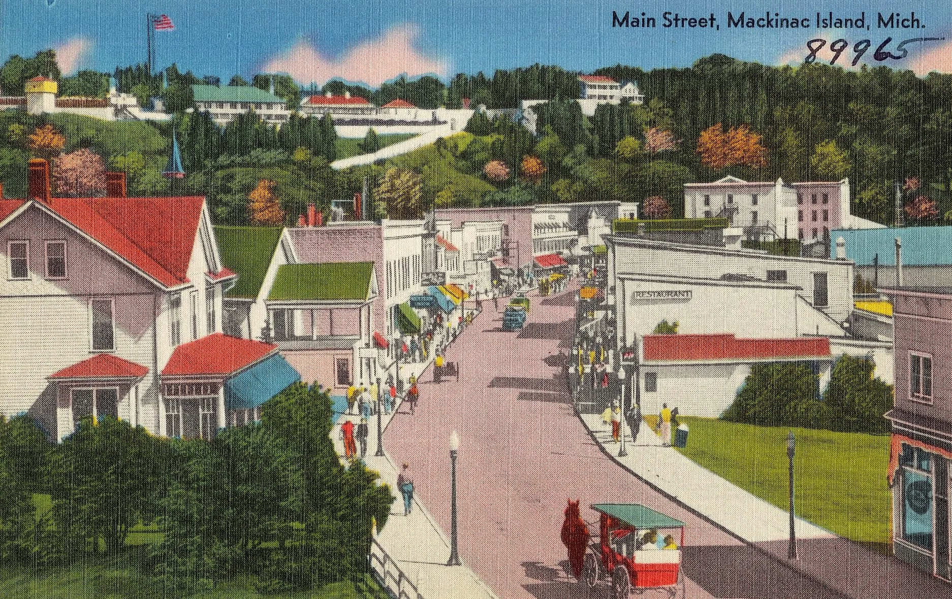 An old colour postcard of Main Street, Mackinac Island, with hotels, a horse-drawn carriage and people walking in the road.