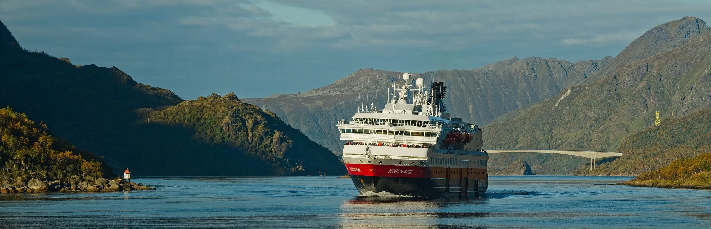 The Hurtigruten ship MS Nordnorge coming through the narrow strait of Raftsundet between steep hills in autumn colour.