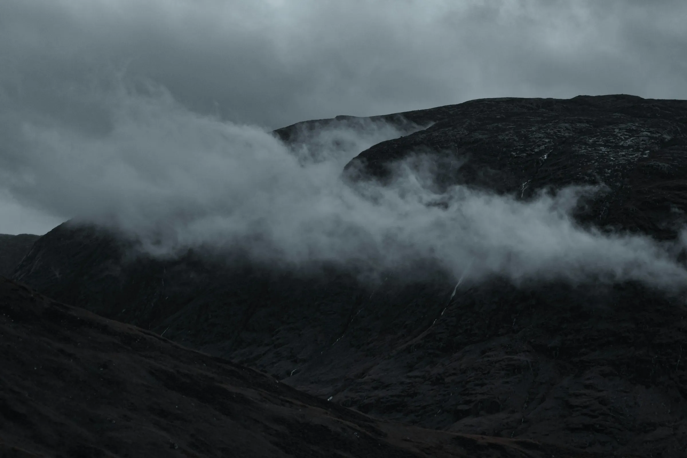 Low cloud drifting across dark hillsides in Glen Etive.