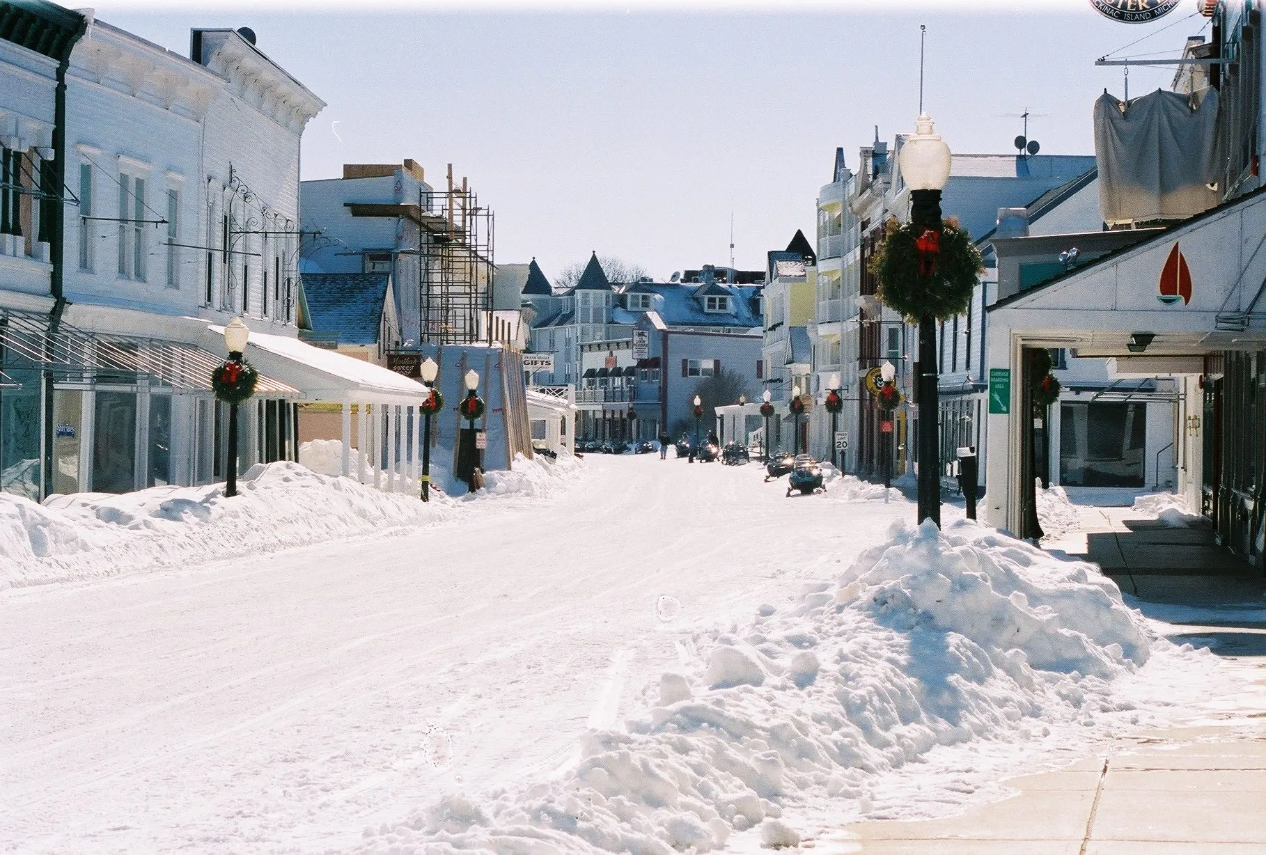 Main Street on Mackinac Island under deep snow, with the shops shut and nobody about.